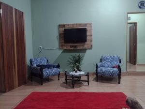 a living room with two chairs and a tv at Martins in Extrema