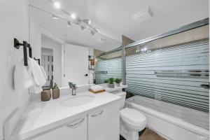 a white bathroom with a sink and a toilet at Chic 1BR Condo in Coal Harbour in Vancouver