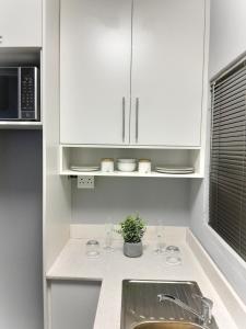 a kitchen with white cabinets and a sink with wine glasses at White City Gardens, Empangeni, Ngwelezana in Empangeni