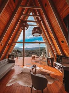 Una sala de estar con una gran ventana en una casa. en Casa Di Legno Cabana incrível com vista para as montanhas, en Urubici