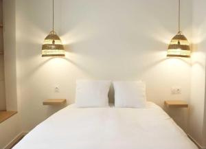 1 dormitorio con 2 lámparas y 1 cama blanca en Charmant studio en plein coeur de Tain l'Hermitage, en Tain-lʼHermitage