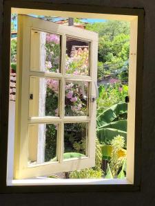 a window with a view of a garden with flowers at Chez Marine Guest House in Búzios