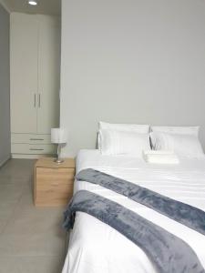 a bedroom with a large white bed and a night stand at White City Gardens, Empangeni, Ngwelezana in Empangeni