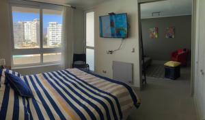 Departamento La Serena Laguna del Mar في لا سيرينا: غرفة نوم بسرير وبطانية مخططة باللون الأزرق والأبيض