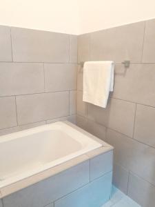 a white bathroom with a tub and a towel at White City Gardens, Empangeni, Ngwelezana in Empangeni