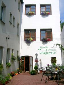 un edificio blanco con mesas y sillas delante en Penzion a Vinoteka Hrozen, en Kroměříž