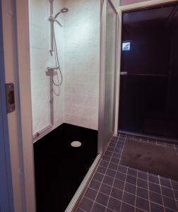 a bathroom with a shower with a tiled floor at SBC Guest House in Pajala