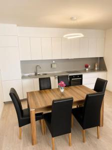 cocina con mesa de madera y sillas negras en City Center Apartment, en Ferizaj