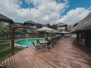 a deck with tables and chairs next to a swimming pool at Apartamento em Barra Grande, Piauí in Cajueiro
