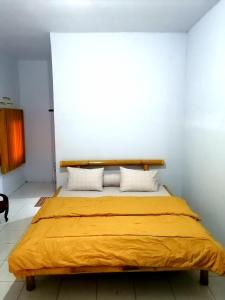 ein Schlafzimmer mit einem Bett mit einer gelben Decke in der Unterkunft Semar88 Guest House in Balong