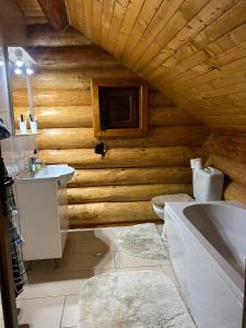 baño con paredes de madera, bañera y lavamanos en Casa Brindusa, en Poiana Negrii