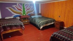a bedroom with two beds and a painting on the wall at Hospedaje La Ñusta in Ollantaytambo