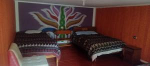 a bedroom with two beds and a painting on the wall at Hospedaje La Ñusta in Ollantaytambo