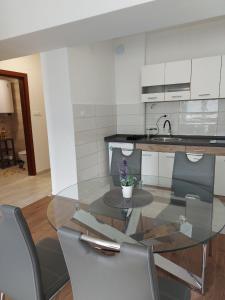 a glass table in a kitchen with chairs and a sink at Relax in Apartment Stela in Skopje