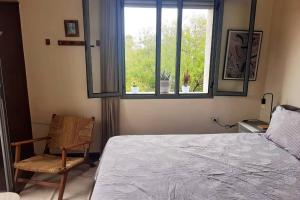 a bedroom with a bed and a chair and a window at The cactus house in Casablanca