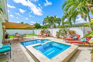 a swimming pool in a backyard with chairs and a table at Walk to The Ave- Heated Pool, Spa, Golden Tee and Putting Green - mins to Beach in Delray Beach