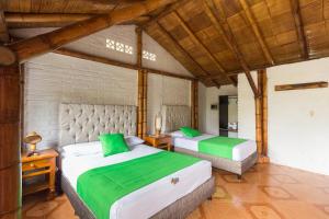 duas camas num quarto com verde e branco em De La Vega Hotel Campestre em Montenegro