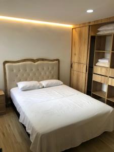 a bedroom with a large white bed and a book shelf at Hermoso y cómodo apto Sabaneta Medellín in Sabaneta