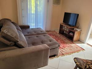 a living room with a couch and a flat screen tv at Apto.luxo superaconchegante 4 pessoas 1vaga garage in Angra dos Reis