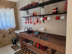 a kitchen with a sink and red utensils on the wall at Apto.luxo superaconchegante 4 pessoas 1vaga garage in Angra dos Reis