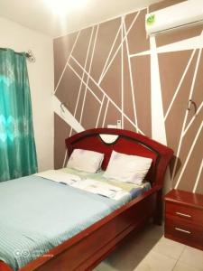Schlafzimmer mit einem Bett mit einem Kopfteil aus Holz in der Unterkunft Ramakyri room in Douala