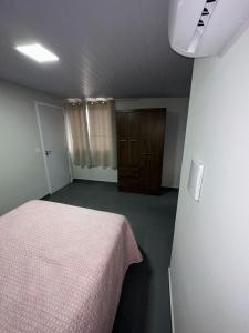 um quarto vazio com uma cama e uma porta em Residencial Wrubleski SC em Pinheira