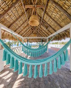 a hammock under a thatched roof on a beach at Hotel Flor de Maria in Puerto Escondido