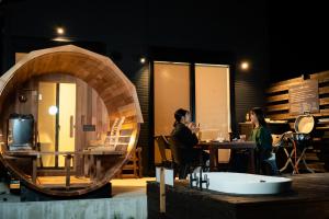 duas pessoas sentadas numa mesa num quarto com uma banheira em SAKURA YAKUSHIMA em Yakushima