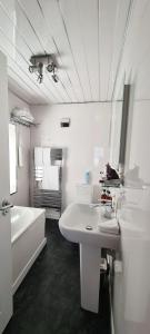 uma casa de banho branca com uma banheira, um lavatório e um espelho. em Cadillac Kustomz Hotel em Rothesay