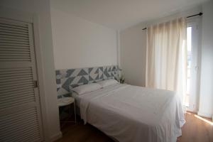 1 dormitorio con cama blanca y ventana en Lavendel Apartments, en Colonia de Sant Jordi