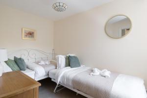 2 bedden in een witte kamer met een spiegel bij Beautiful cottage style 3-bed By Valore Property Services in Loughton