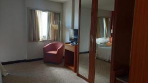 a hotel room with a chair and a mirror at Flat Particular no Comfort Suites in Brasilia