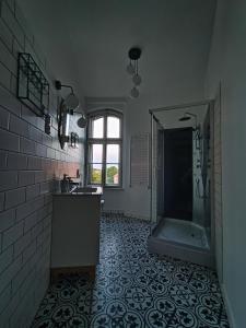 ein Bad mit einer Dusche, einem Waschbecken und einem Spiegel in der Unterkunft Wieża Gniezno Apartament KRÓLOWA in Gniezno