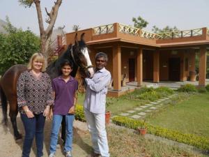 a man and a woman and a horse in front of a house at Krishna Ranch in Udaipur