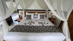 Schlafzimmer mit einem großen Bett und weißen Vorhängen in der Unterkunft Bayad anyar - Ubud Bali in Ubud