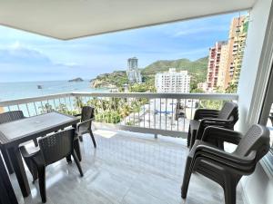 balcón con sillas, mesa y vistas al océano en Caribbean Venture Apto 901- Rodadero, Santa Marta, en Santa Marta