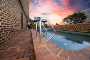 een zwembad met een leuning naast een gebouw bij Best Western Cattle City Motor Inn in Rockhampton