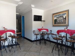 a room with red tables and chairs and a flat screen tv at Pousada Ouro Preto in Ouro Preto