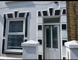a white house with a door and two windows at Samarlon Home Saxton in Gillingham