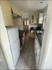 uma pequena cozinha com electrodomésticos brancos e pisos em madeira em Samarlon Home Saxton em Gillingham