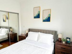 um quarto com uma cama com lençóis brancos e pinturas na parede em Prime Location! 3BRGem near University of Chicago em Chicago