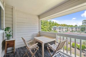 uma varanda com uma mesa de madeira e cadeiras em Peaceful Treetop Condo - 2br/2ba em Hilton Head Island