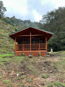 eine große Holzhütte auf einem Feld mit Bäumen in der Unterkunft Chalet Amauleza in San Gerardo de Dota