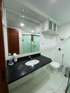 Un baño con lavabo, inodoro y espejo. en Arraial do Cabo, Loft Visão do Paraíso, en Arraial do Cabo