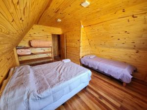 a bedroom with two beds in a log cabin at Cabañas Jardines in Bella Unión