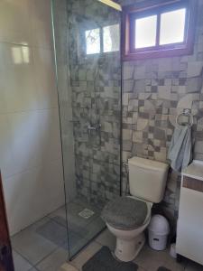 a bathroom with a toilet and a glass shower at Cabañas Jardines in Bella Unión