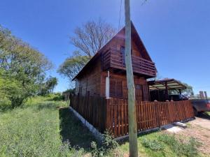 una casa de madera con una valla delante en Cabañas Jardines en Bella Unión