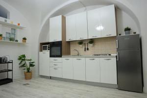 una cucina con armadietti bianchi e frigorifero nero di MOUSUITE a Catania