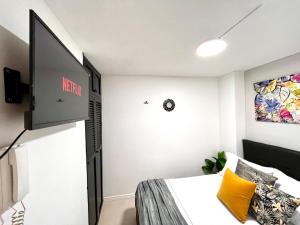 a bedroom with a bed and a flat screen tv at Apartaestudio Encanto Pacífico in Cali