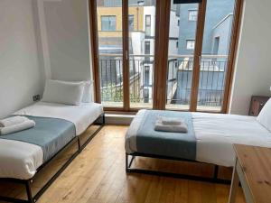2 Betten in einem Zimmer mit einem großen Fenster in der Unterkunft Shad Thames by condokeeper in London
